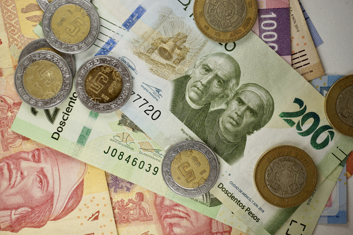 Many mexican pesos bills spread randomly over a flat surface