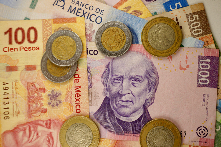 Many mexican pesos bills spread randomly over a flat surface