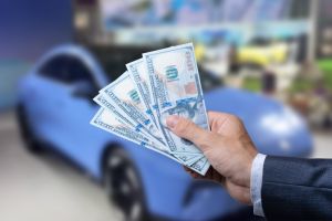 Man with 100 dollar banknotes money near car. Buy or rent a new auto. Finance concept.