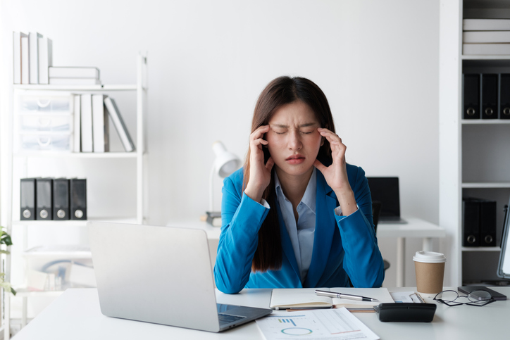 Tired and stressful Asian office worker having a hard time trying to focus on her work, feeling tried after working a long day.