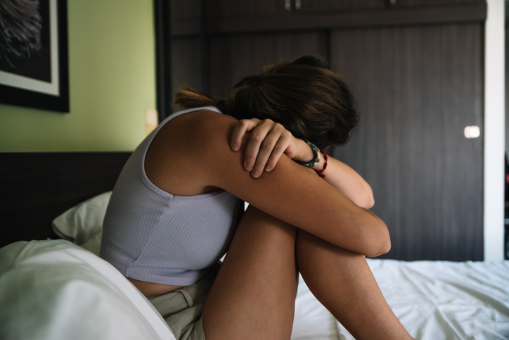 Young woman with depressive state sitting up in bed. Concept of mental health