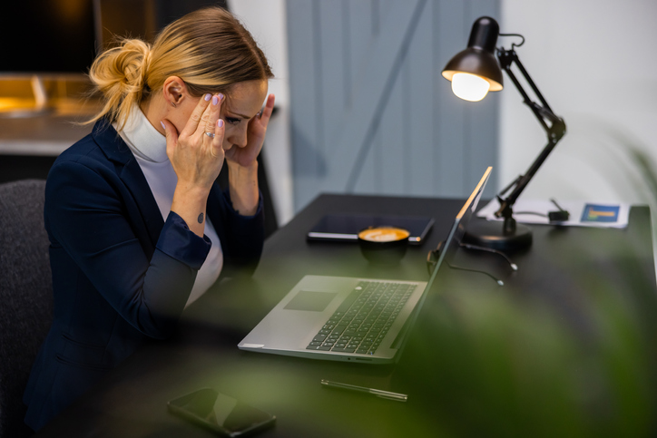 Blond female entrepreneur with head in hands at office