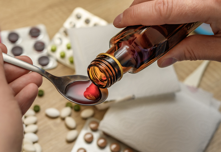 Cough syrup in a bottle poured on a spoon