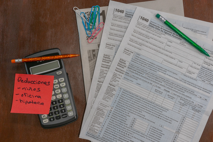 flat lay on wood background, 1040 tax forms in Spanish with calculator