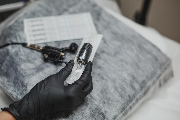 a permanent make-up machine and a disposable needle lie on a couch 1