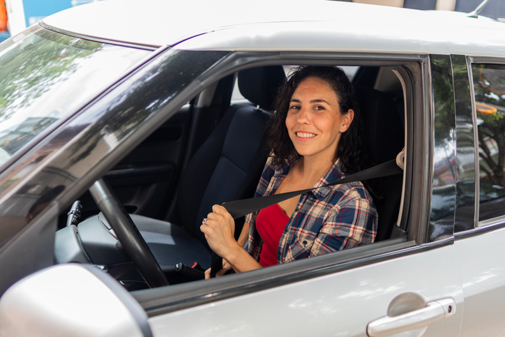 Portrait of a mid adult woman putting seat belt inside the car