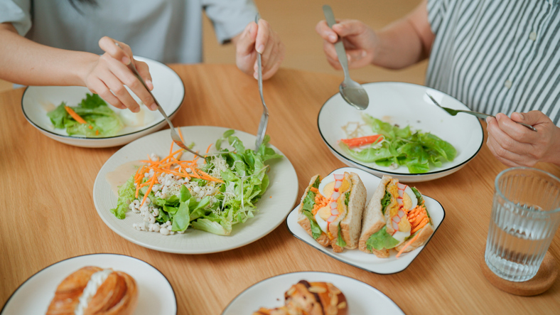 Elderly Asian woman enjoying green salad for dinner with her daughter.