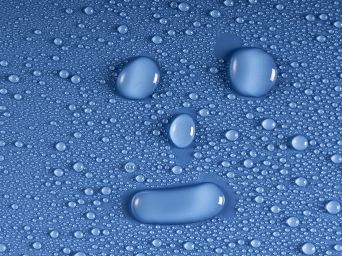 Small water drops in the shape of a happy human face on a blue background.