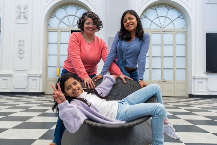 Mother and daughters pose for a picture in front of a white building