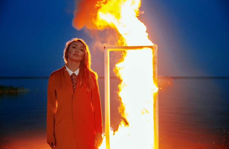 Woman standing in front of the burning door at the sea. Nicely fit for book cover
