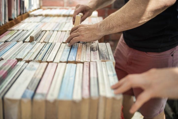 Close-up of two male friends buying books at flea market