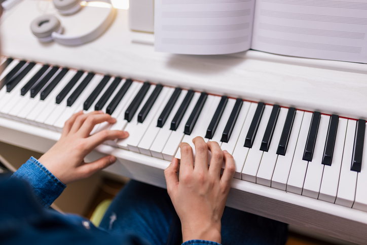 Boy plays piano at home from notes.
