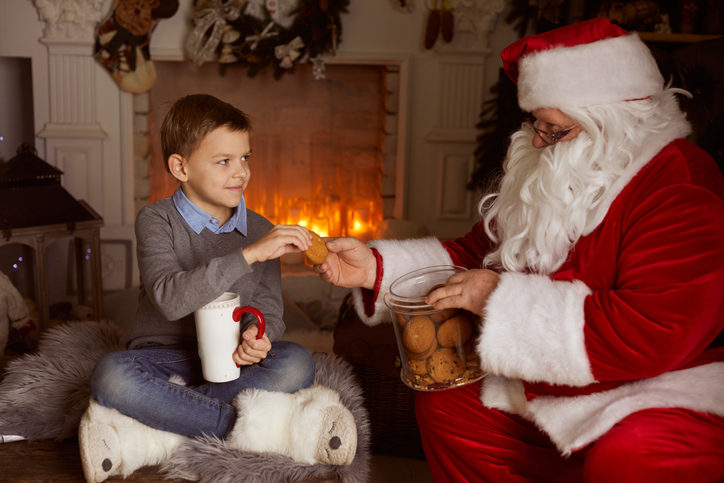 Santa and a boy are reading a book at Santa's house,