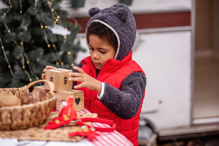 Child Stacking Wooden Blocks Outdoors During Holiday Season