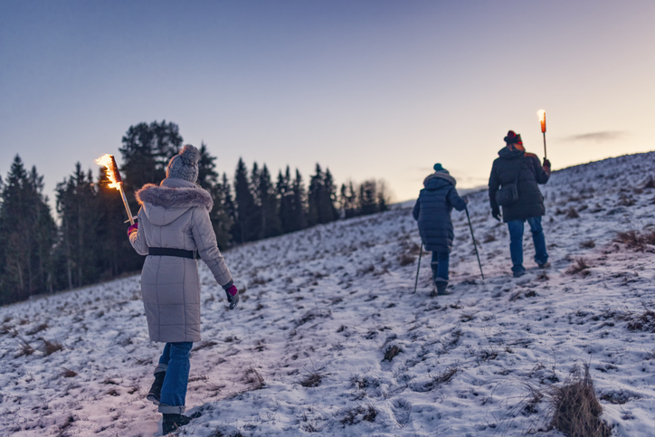 Senior couple and mature woman walking in on hill with flaming torches