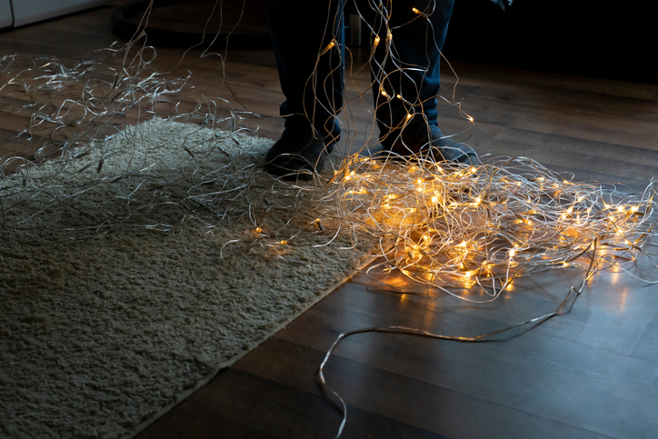 Man unravels a christmassy chain of lights.