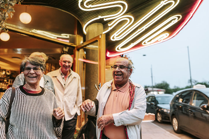 Happy senior man enjoying with male and female friends outside restaurant
