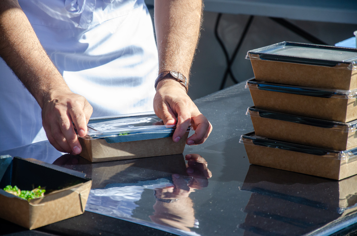 Close-up of prepared food placed in containers at an outdoor open kitchen