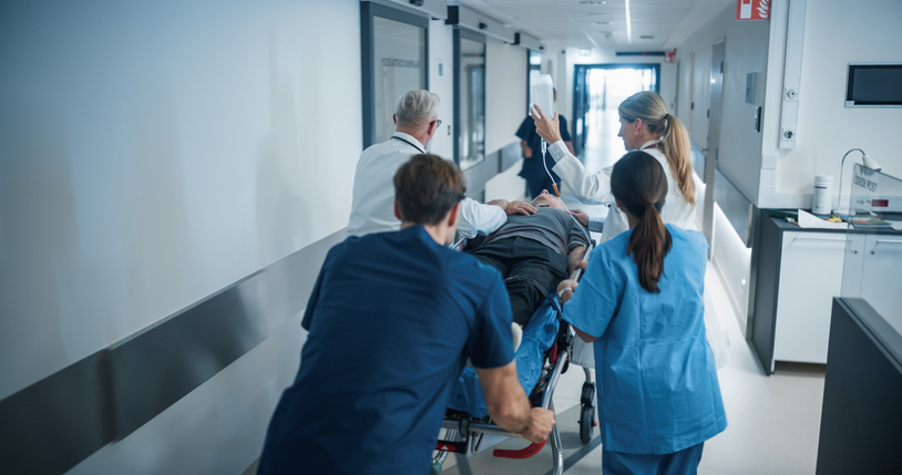 Diverse Emergency Medical Team Rushing Down a Hospital Corridor, Carefully Pushing a Stretcher with an Injured Patient. Nurses and Doctors Coordinate the Urgent Situation