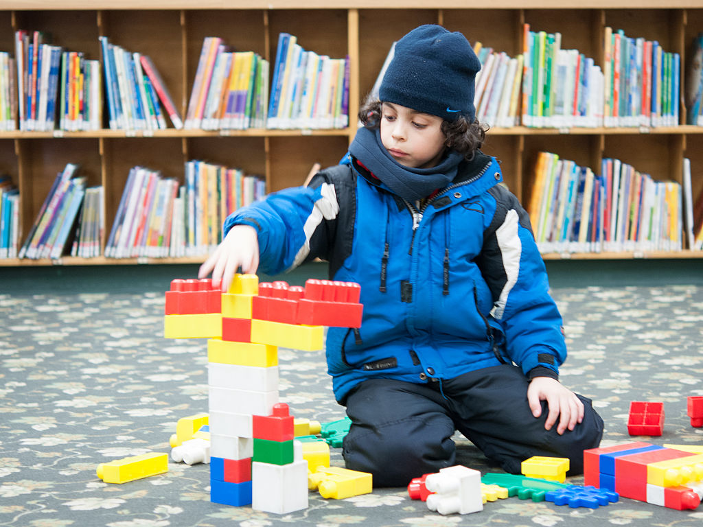 Boy playing with Legos in Toronto Public Library. He is...