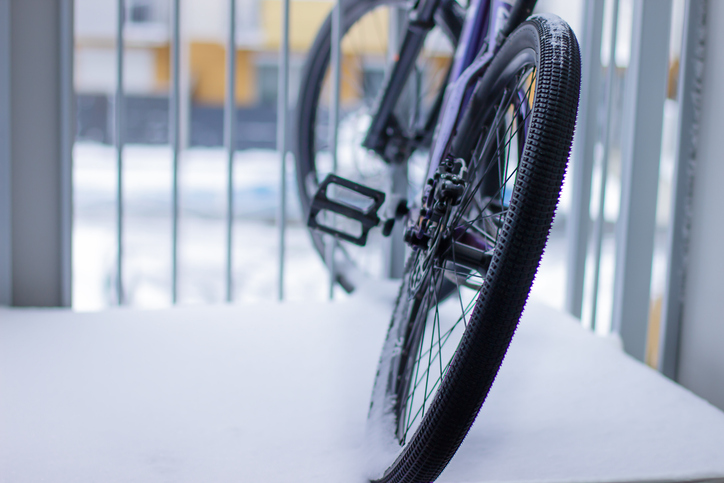 The wheels of a bicycle standing on the balcony of an apartment in the city