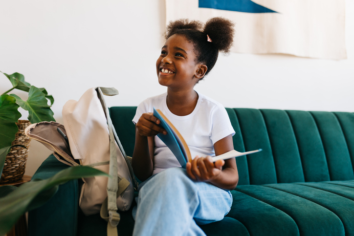Black girl reading a book in the living room at home