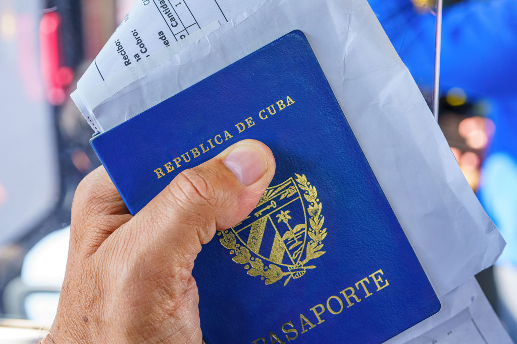 Hand of a man holding a Cuban passport and the receipts for...