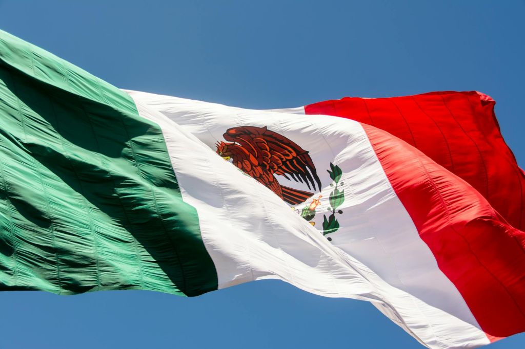 close up of mexican flag waving against blue sky