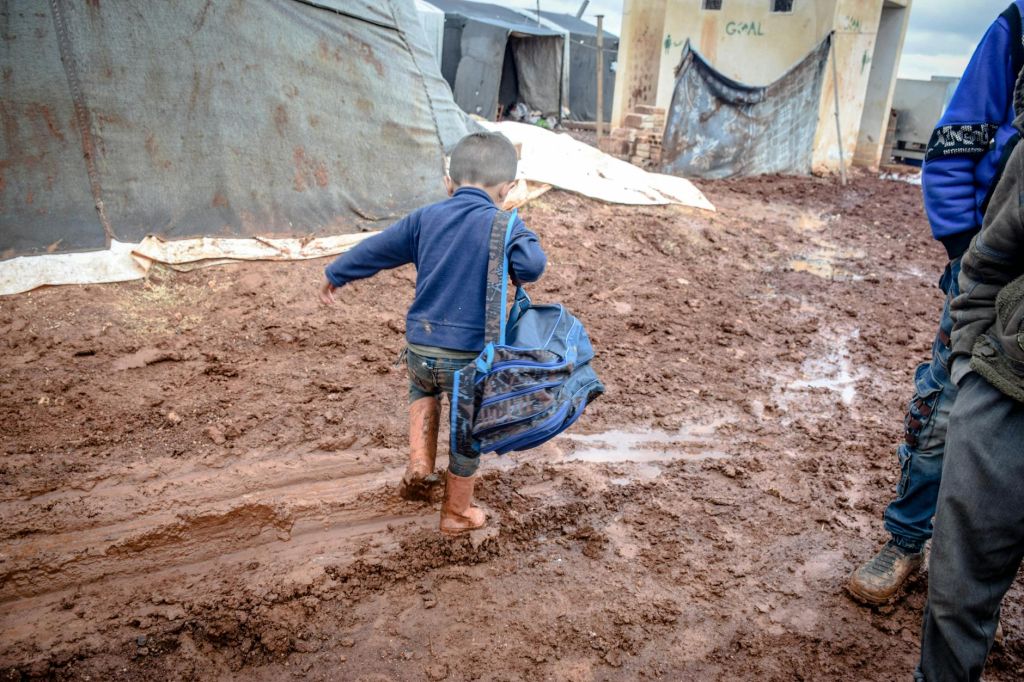 boy with dirty legs and backpack strolling in village