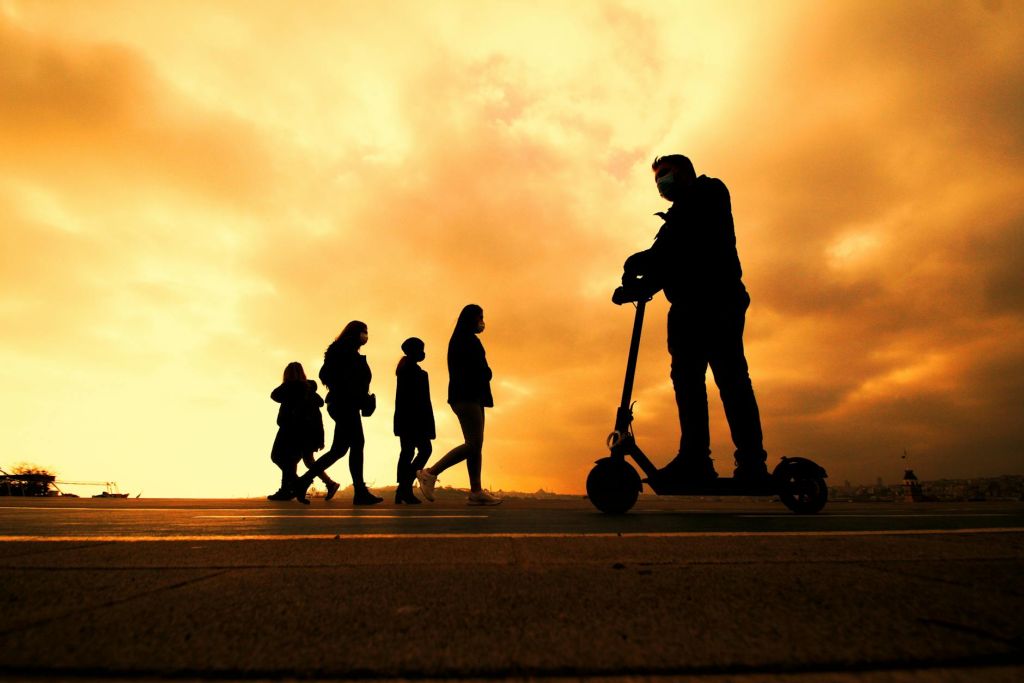 silhouettes of people walking in city on the background of an orange sunset sky