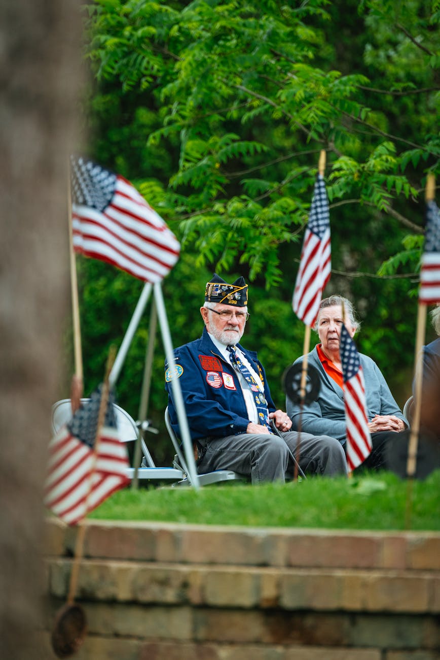 man in uniform and woman sitting at cemetery with flags of the usa