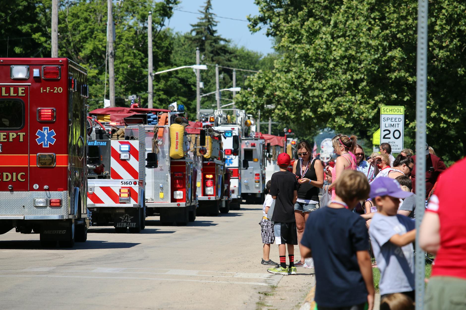 row of fire engines passing crowd of people