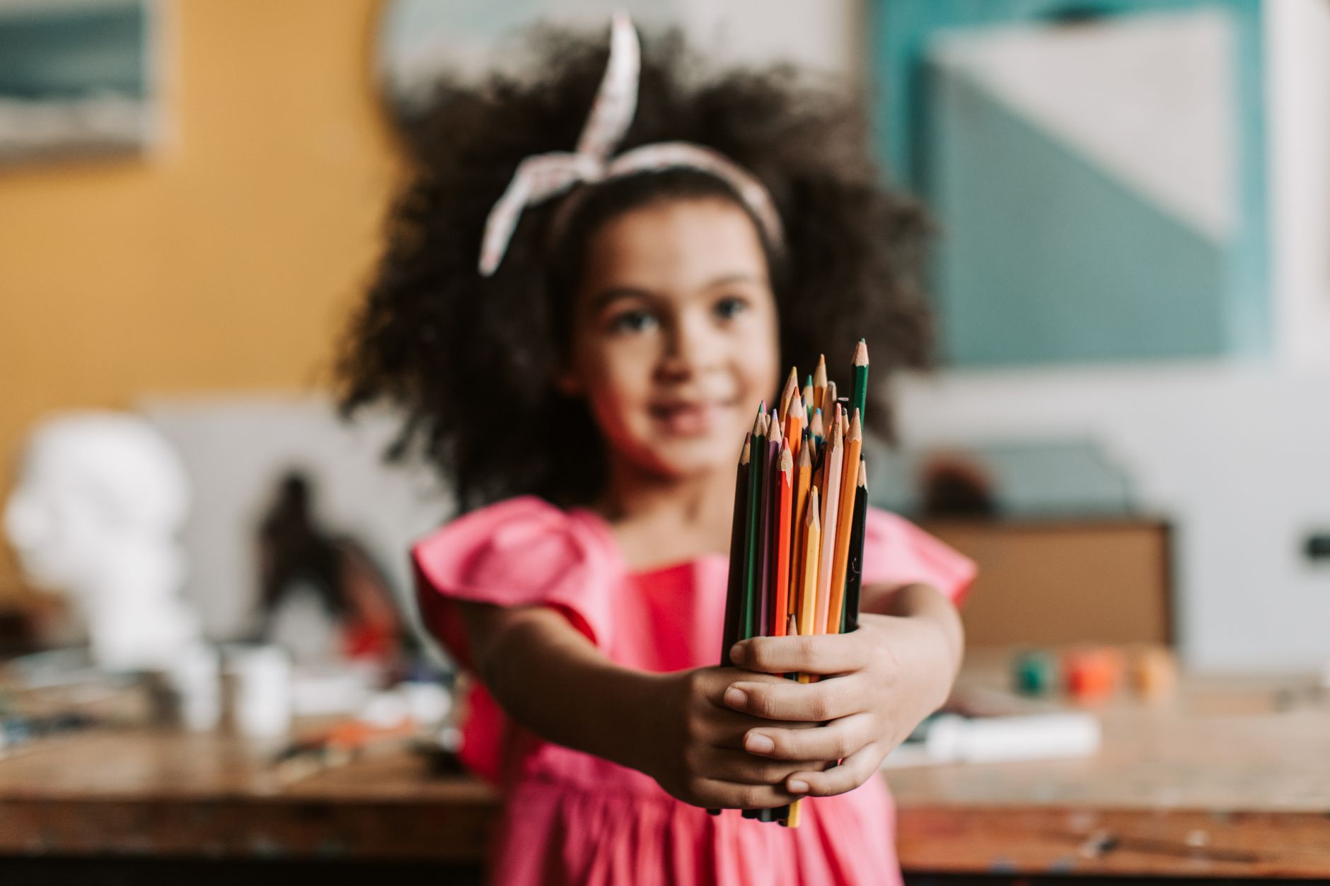 photograph of a girl holding colored pencils