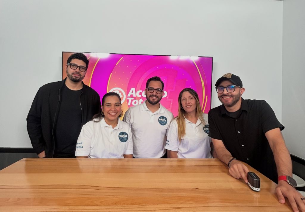 Five people posing behind a desk with "Acorn TV" branding on a screen behind them.